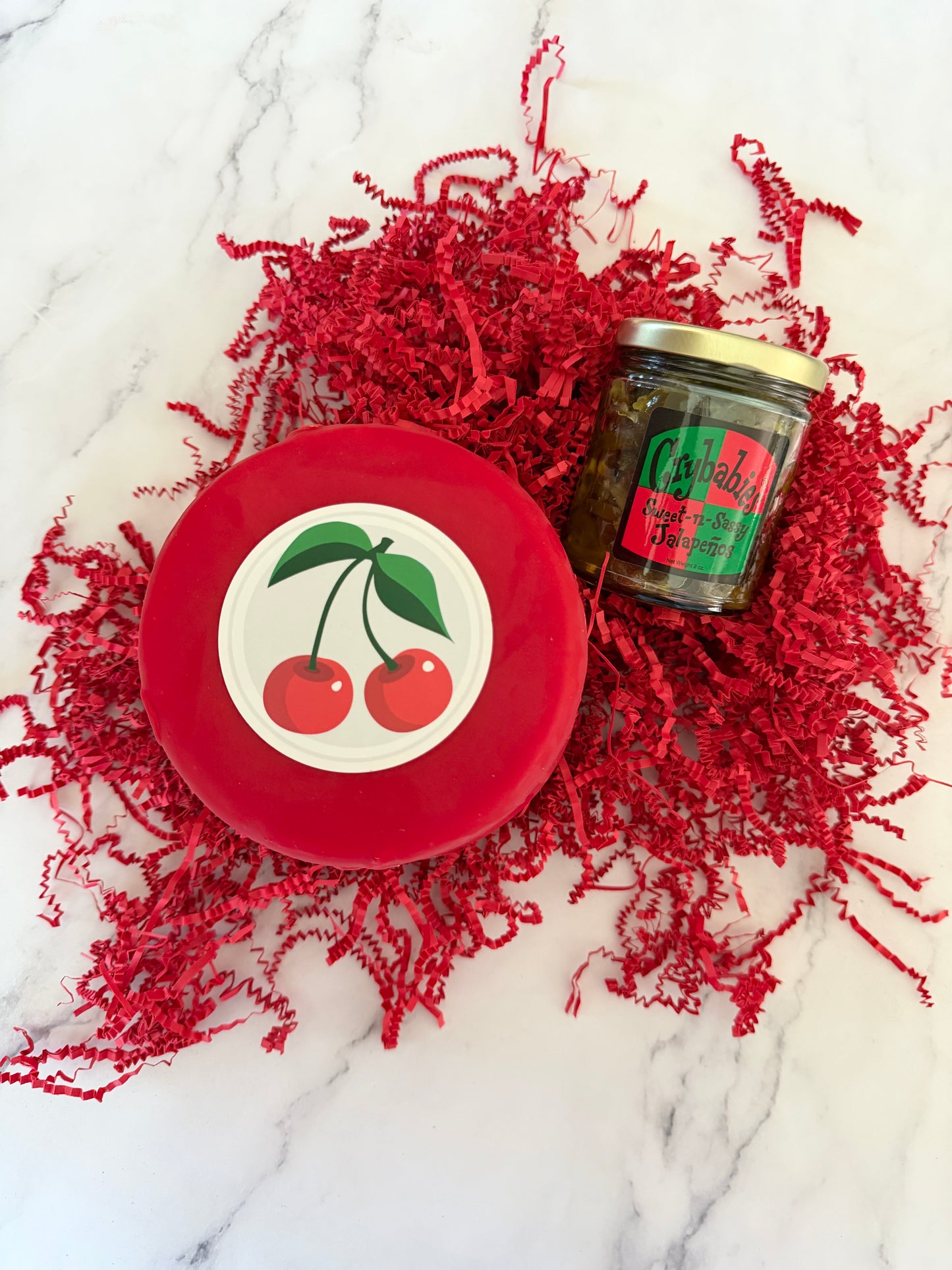 Red container with cherry design lid on a textured red fabric background