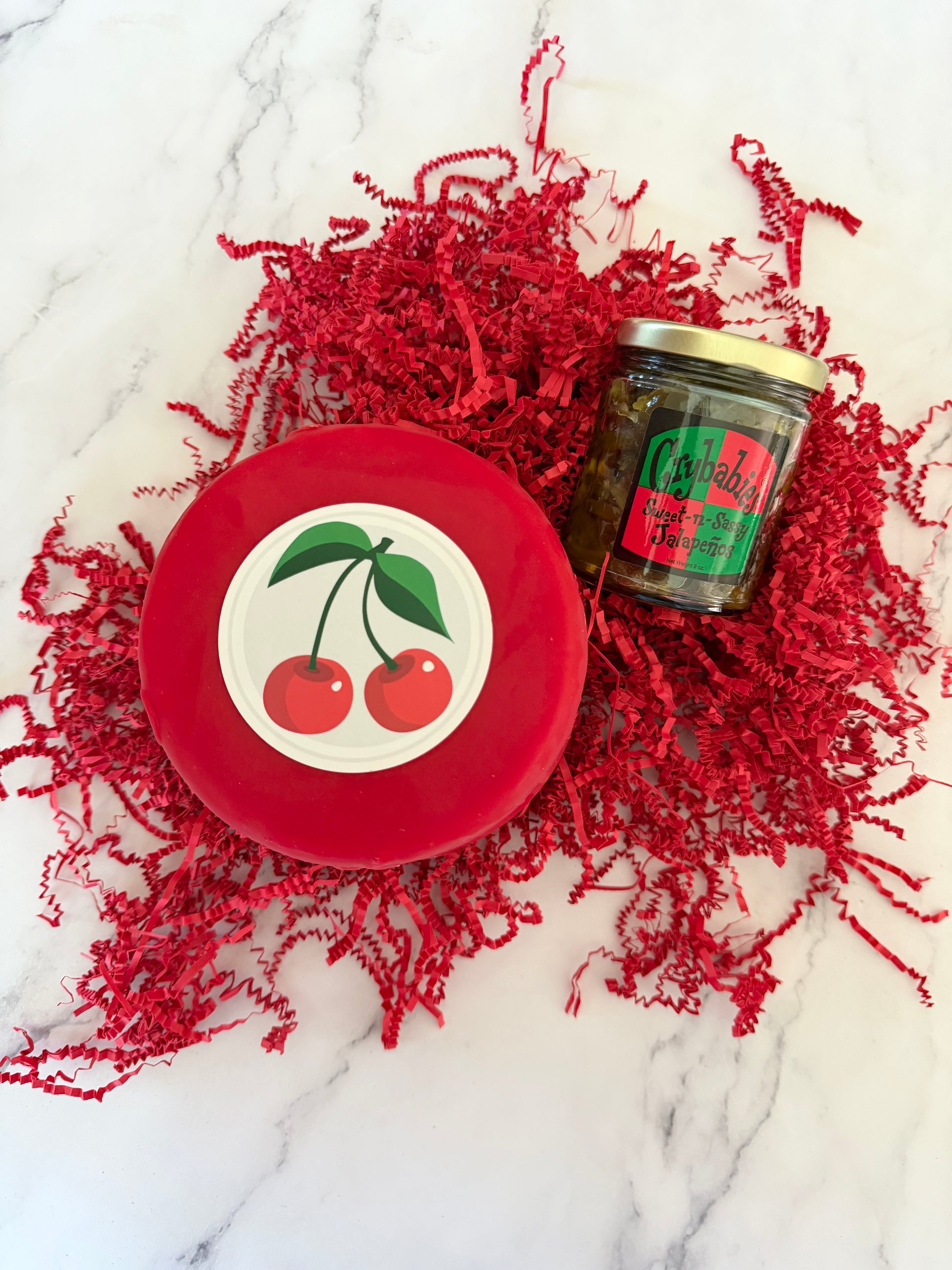 Red container with cherry design lid on a textured red fabric background